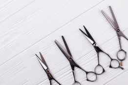 Hairdressing scissors on white wooden background. Steel barbers scissors and copy space.